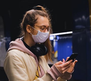 Person wearing a face covering whilst using a phone