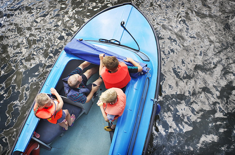 One adult and three children on a blue boat