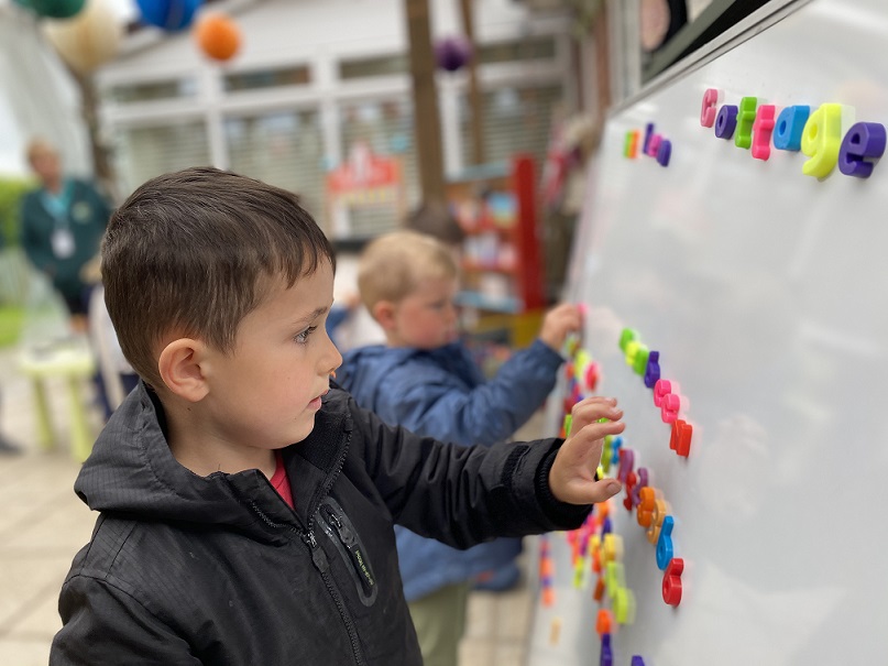 Child, using the magnetic letters on the whiteboard 
