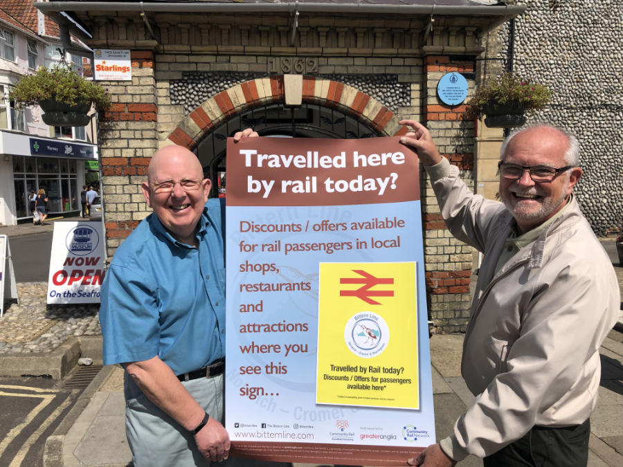 Peter Mayne and John Roseby holding discount campaign poster