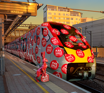 Red hare sticking Great British Rail Sale stickers on a Greater Anglia train