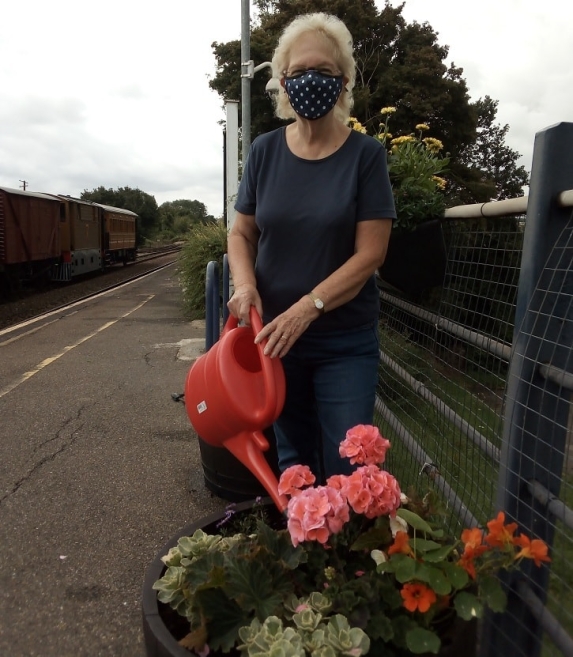 Katherine Beck, a Chappel and Wakes Colne station adopter holding a plastic watering can next to plants