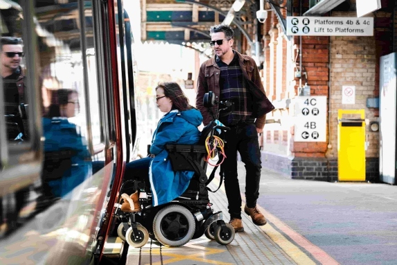Woman in a wheelchair gets on train by using retractable step 