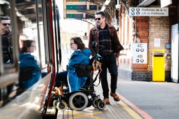 : A woman in a wheelchair getting onto a new Greater Anglia train without assistance due to the retractable step bridging the gap between the train and the platform