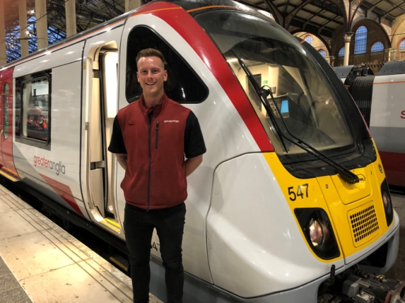 Greater Anglia driver, Joe Compton, posing outside the cab of a new 720 at Liverpool Street Station