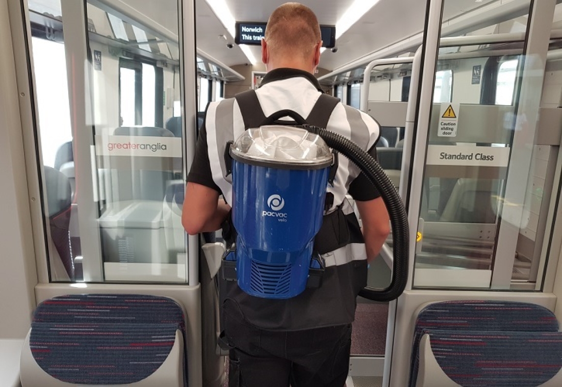 A person wearing a backpack vacuum cleaner on a train.