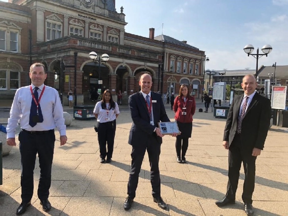 Staff standing outside Norwich station with the 'Large Station of the Year' award