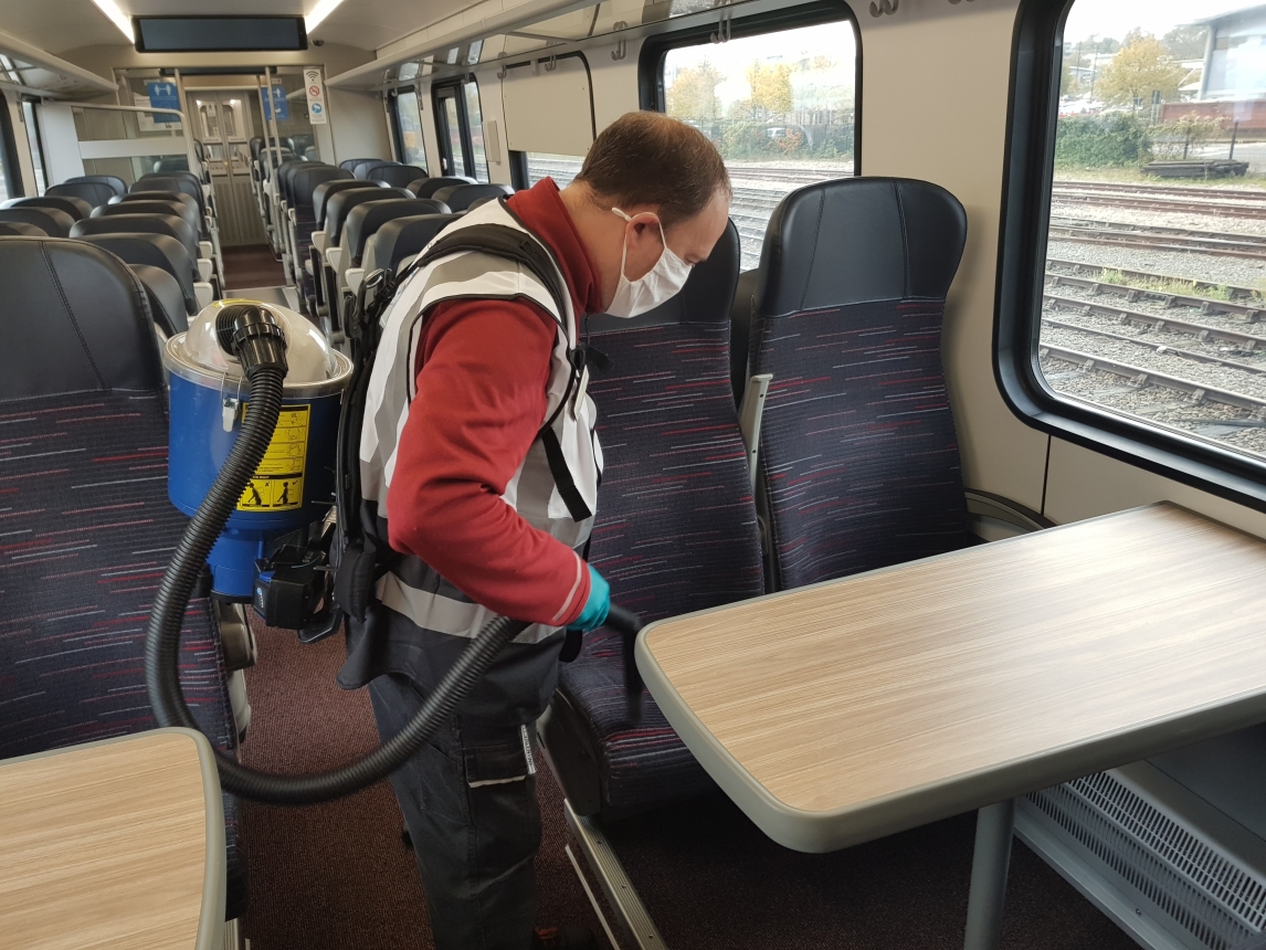 Man wearing high visibility jacket and face mask using backpack vacuum cleaner