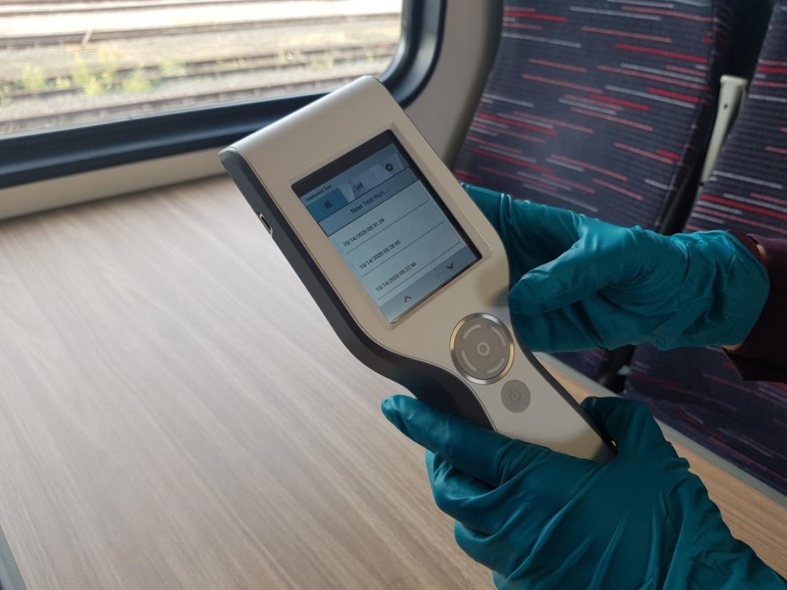 Picture of someone wearing blue gloves, holding a hygiene monitor 