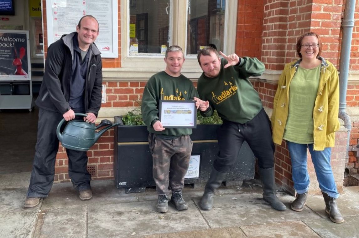Members of Mudlarks, adopters of Hertford East station, with their planter.